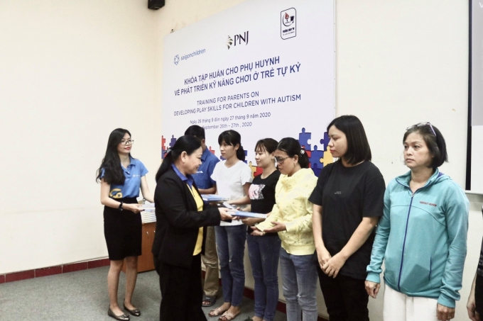 Đại diện PNJ trao tặng cho các phụ huynh bộ tài liệu hỗ trợ và phục hồi chức năng cho trẻ em tự kỷ. Ảnh: PNJ