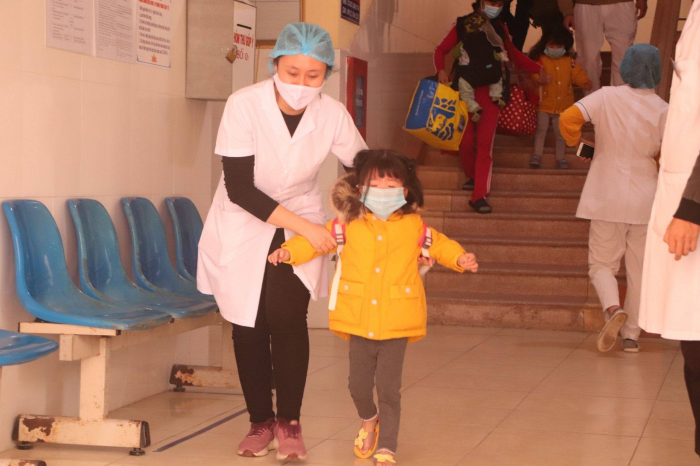 Nhân viên y tế đang đưa cháu bé ra khỏi Trung tâm y tế TP. Chí Linh. Ảnh: PV