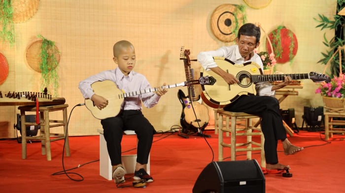 Ông Trần Nên biểu diễn ngón đàn guitar cùng với tài năng nhí bé Khánh Hưng. Ảnh: NVCC