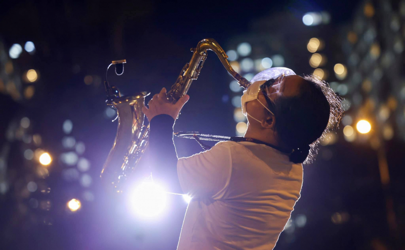 Nghệ sĩ saxophone Trần mạnh Tuấn đeo chiếc khẩu trang được khoét lỗ say sưa cất lên giai điệu bài hát Quê hương trong khu bệnh viện dã chiến điều trị Covid-19. Ảnh: TL