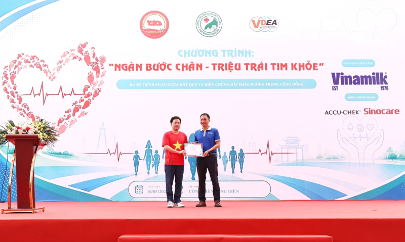 Ông Vũ Tuấn Khang (áo xanh) - Giám đốc Kinh doanh Hà Nội, Công ty Cổ phần sữa Việt Nam (Vinamilk) – nhận chứng nhận tài trợ từ Ban tổ chức chương trình “Ngàn bước chân – Triệu trái tim khỏe”. Ảnh: VN. 